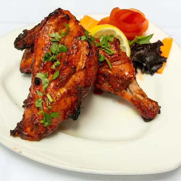 Manhattan Valley Indian Restaurant's Tandoori Chicken, garnished with cilantro, lemon, and carved vegetables.