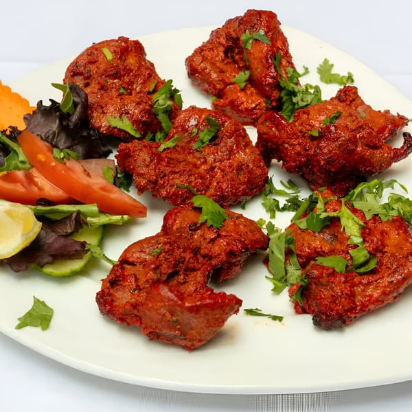 Manhattan Valley Indian Restaurant's chicken tikka, garnished with cilantro and a side salad.