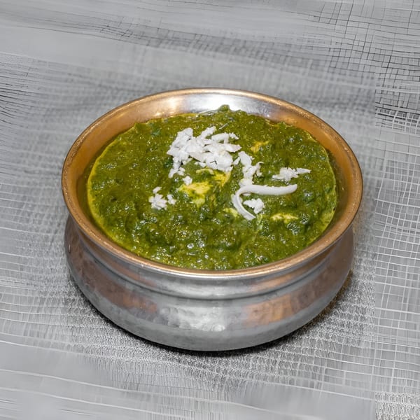 Palak Paneer, a vibrant green Indian spinach and cheese dish, served in a rustic metal bowl.